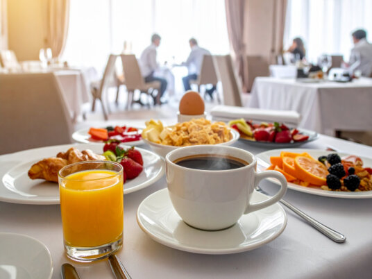 Frühstückstisch im Hotel mit Brötchen, Aufschnitt und Kaffee.